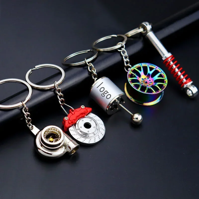 Keychains of car parts: brake caliper, turbocharger, rim and piston with crank on dark background.