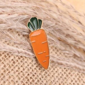 enamelled carrot-shaped badge with orange and green design
