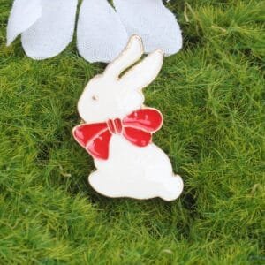 Enamelled white rabbit pin with red ribbon