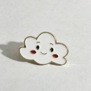 White enamel cloud with black eyes, smile, and rosy cheeks with golden outline pin accessory