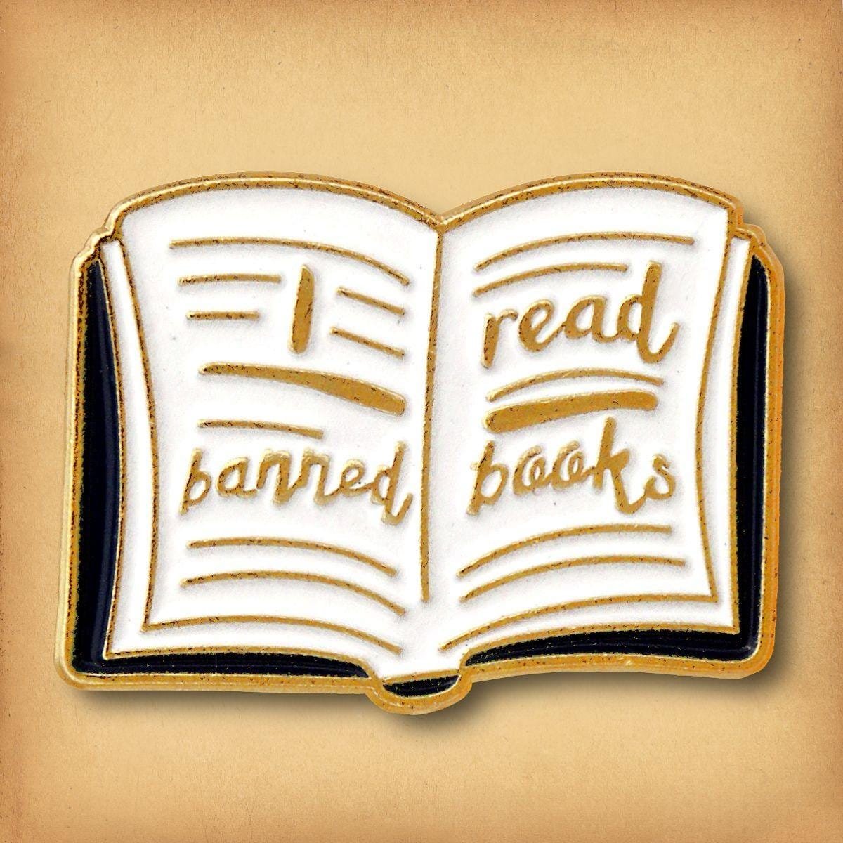 Open white book with gold lettering I read banned books enamel pin literature